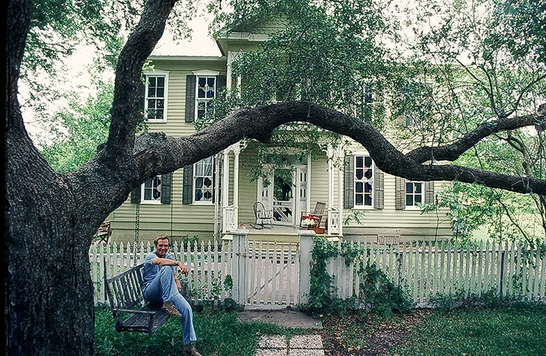 Clovis sitting on the porch swing hanging from the live oak in front of the Macdanial House.