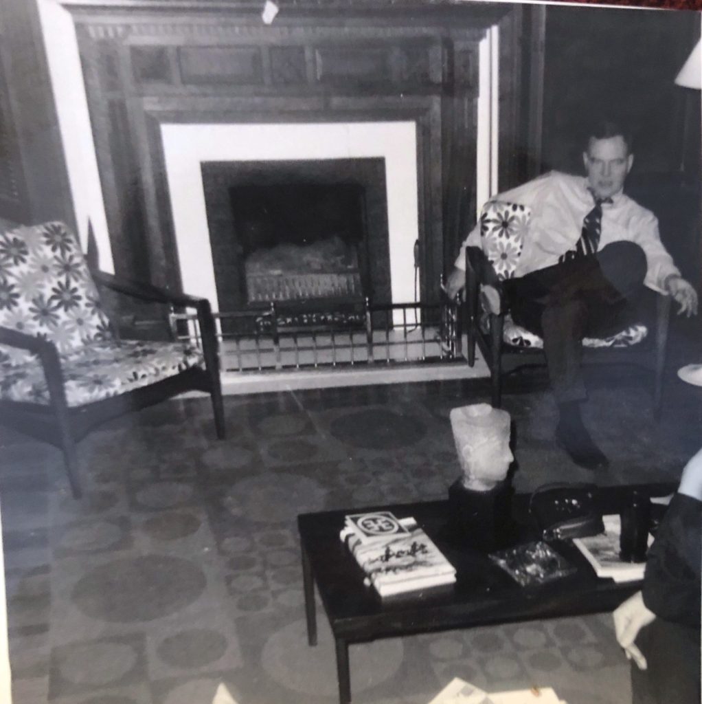 Clovis seated next to the living room fireplace.