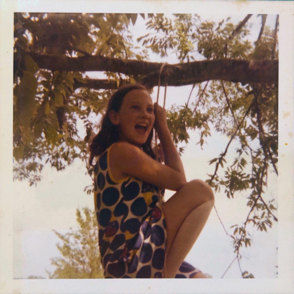 Anne Macdaniel swinging from the rope over the tree branch in back of the house over the pond.