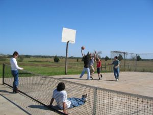 A group of family members playing basketball on the tennis court